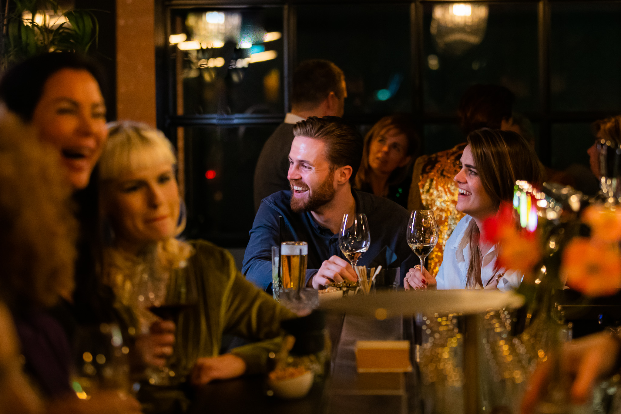 Gasten praten samen met een drankje aan tafel bij H32
